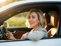 Smiling Blonde Woman Sitting in Luxury Car During Golden Hour.jpeg